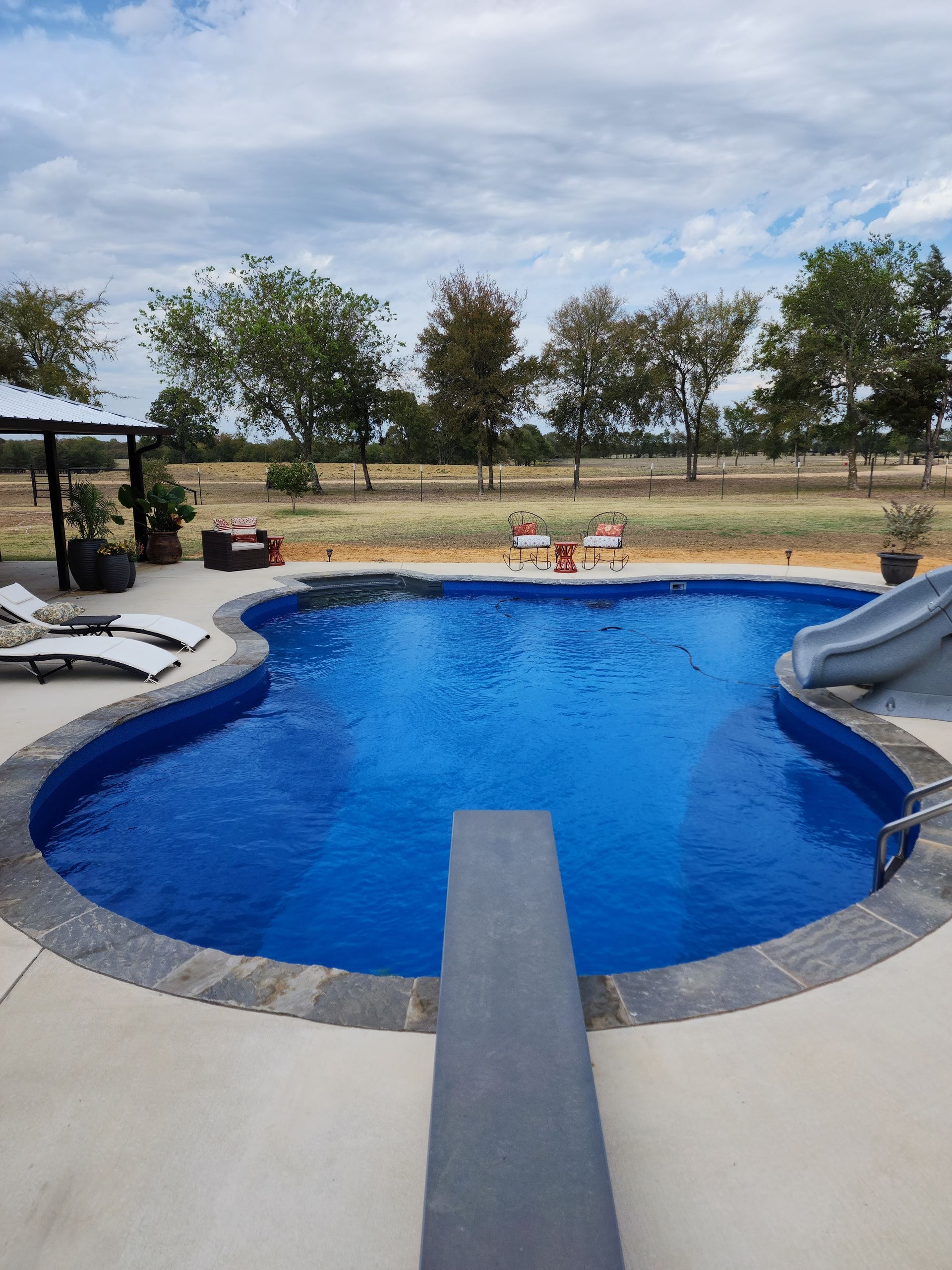 A large swimming pool with a slide and a diving board.