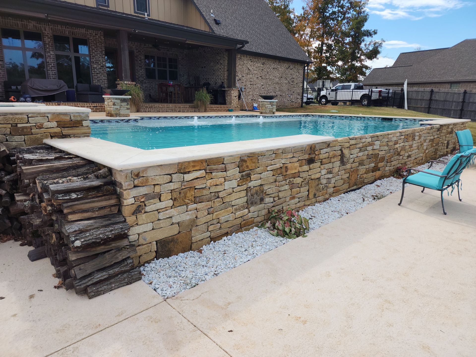A large swimming pool is surrounded by a stone wall.