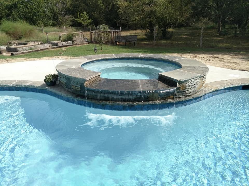 A swimming pool with a hot tub in the middle of it.