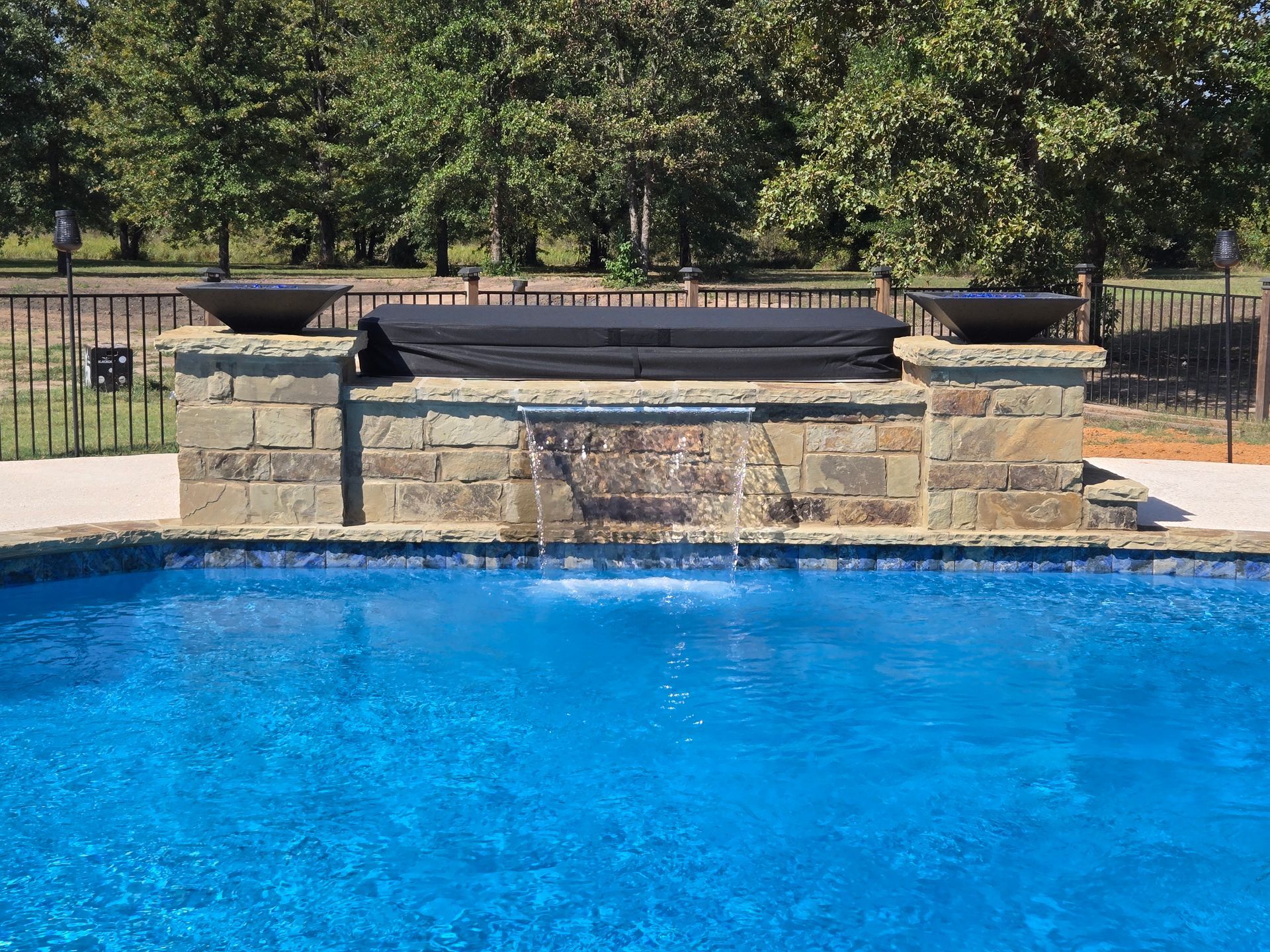 A large swimming pool with a waterfall in the middle.