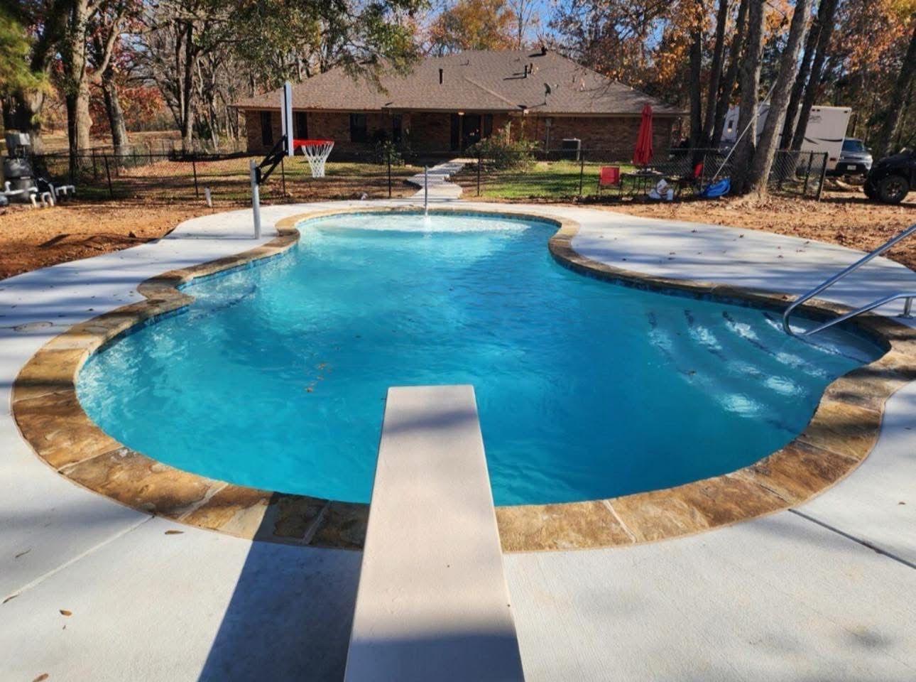 A large swimming pool with a diving board in the middle.