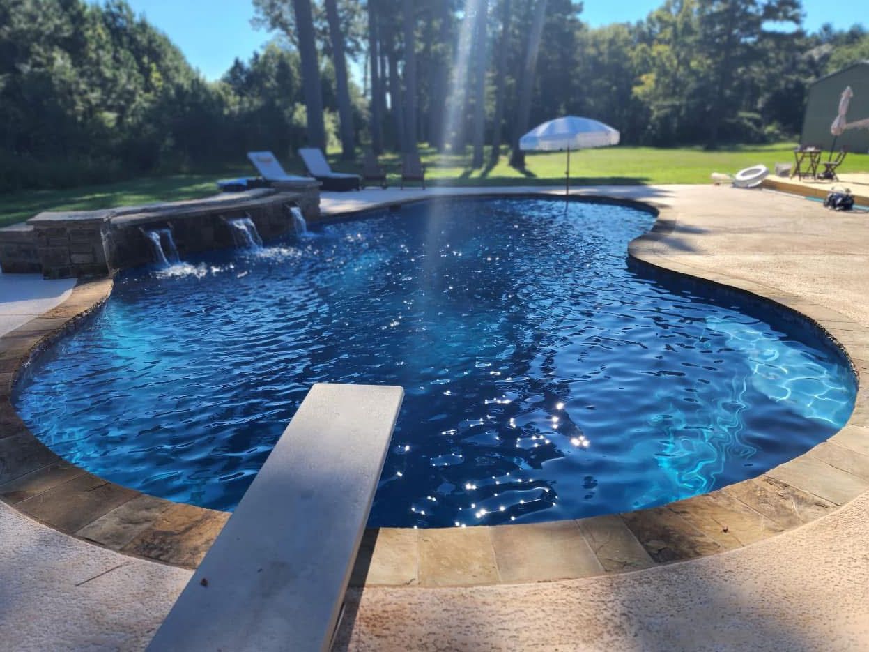 A large swimming pool with a diving board in the middle.