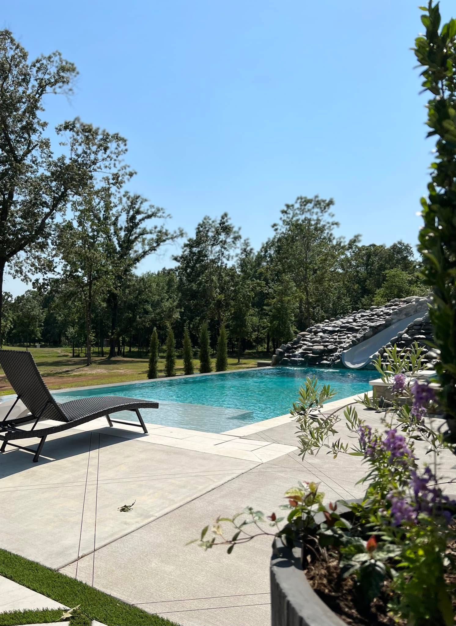 There is a large swimming pool with a slide in the background.