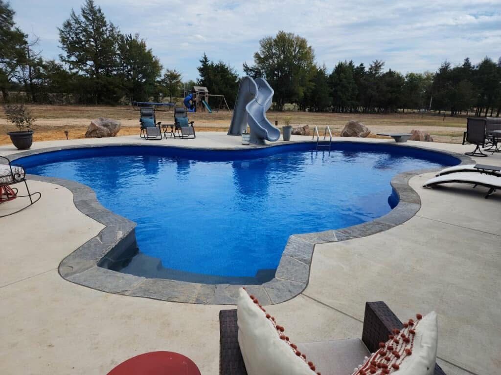 A large swimming pool with a slide in the backyard.