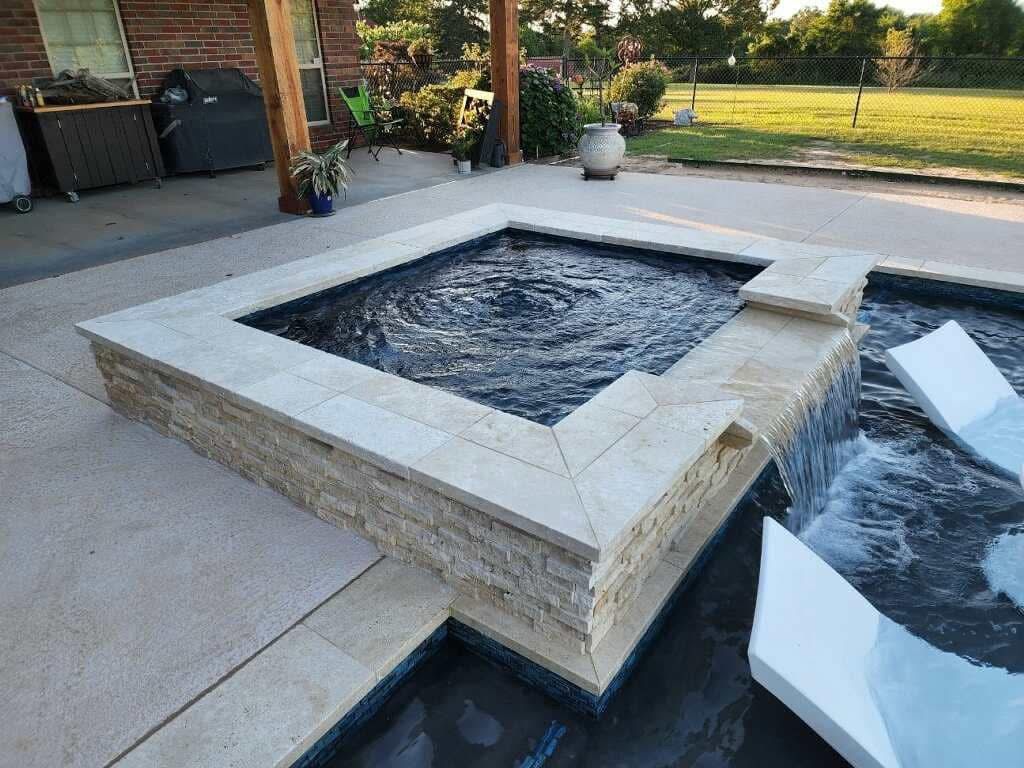 A square pool with a waterfall in the middle of it.