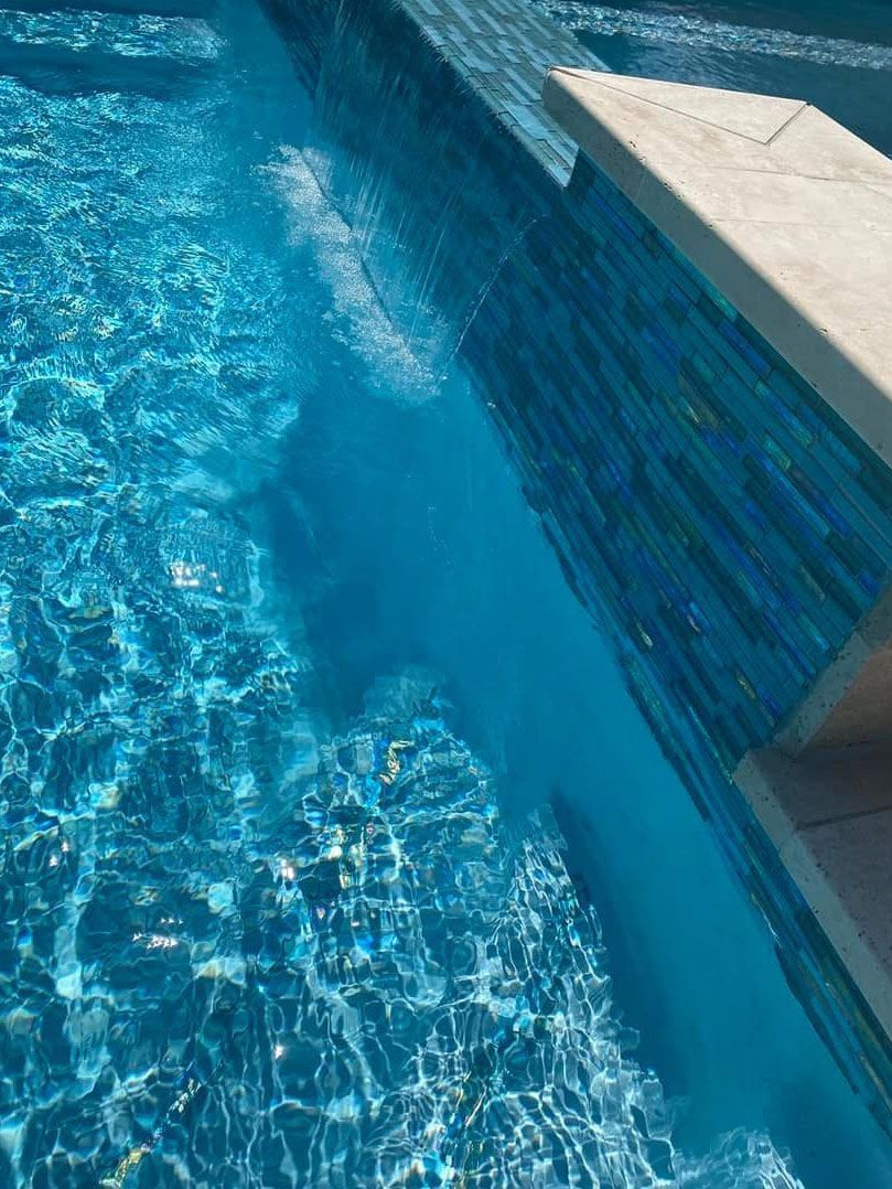 A person is swimming in a blue swimming pool.