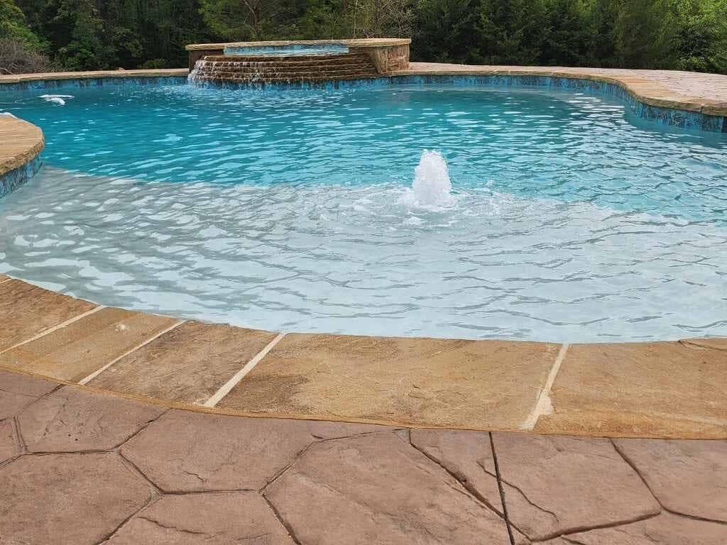 A large swimming pool with a fountain in the middle of it.