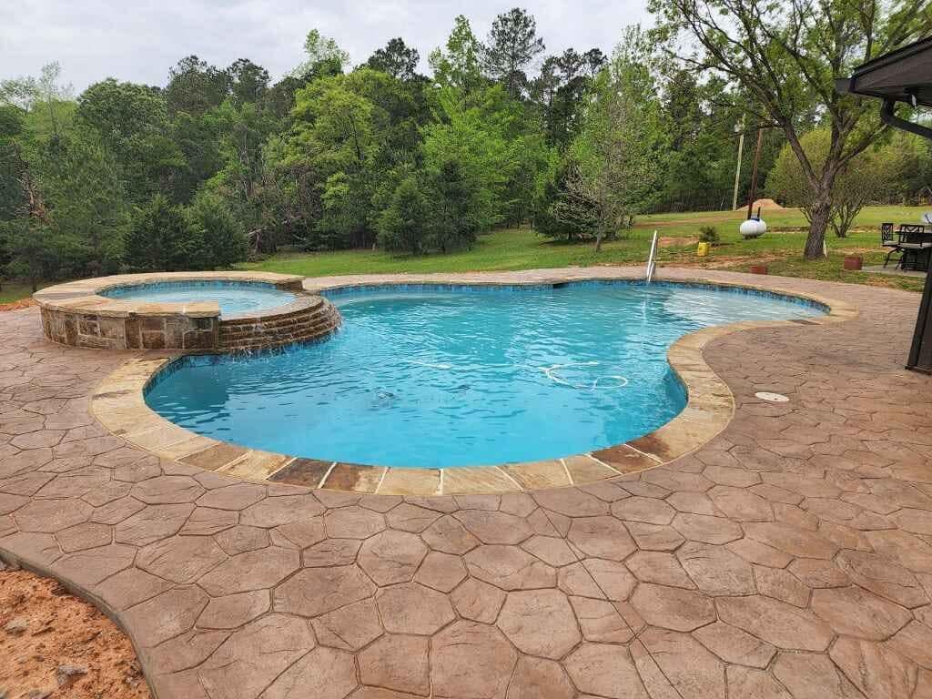 A large swimming pool surrounded by trees and a patio.