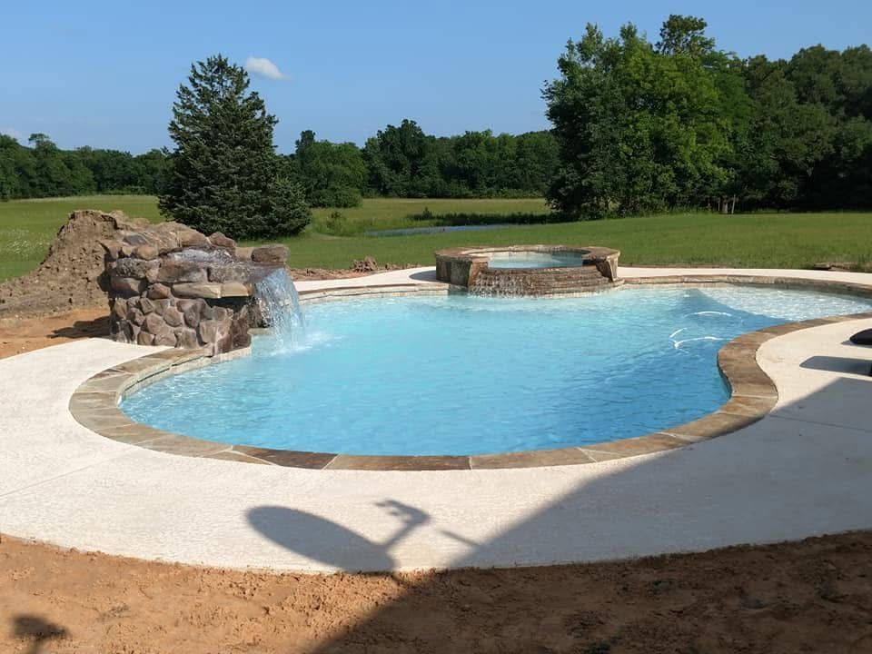 A large swimming pool with a waterfall in the middle.