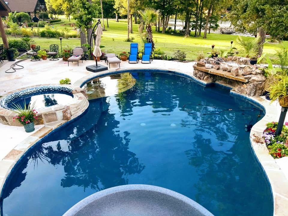 A large swimming pool with a slide and chairs around it.