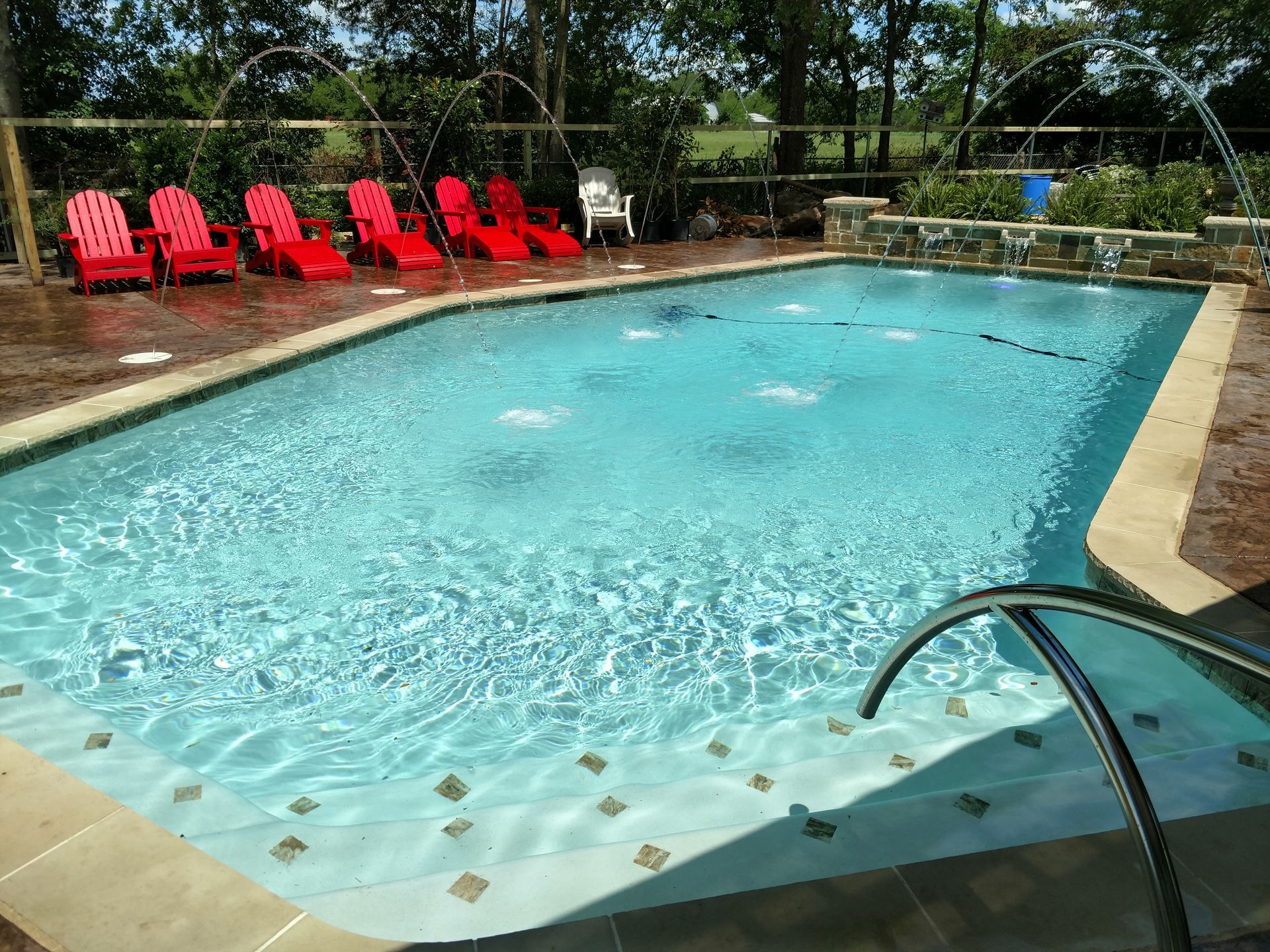 A large swimming pool with red chairs around it.