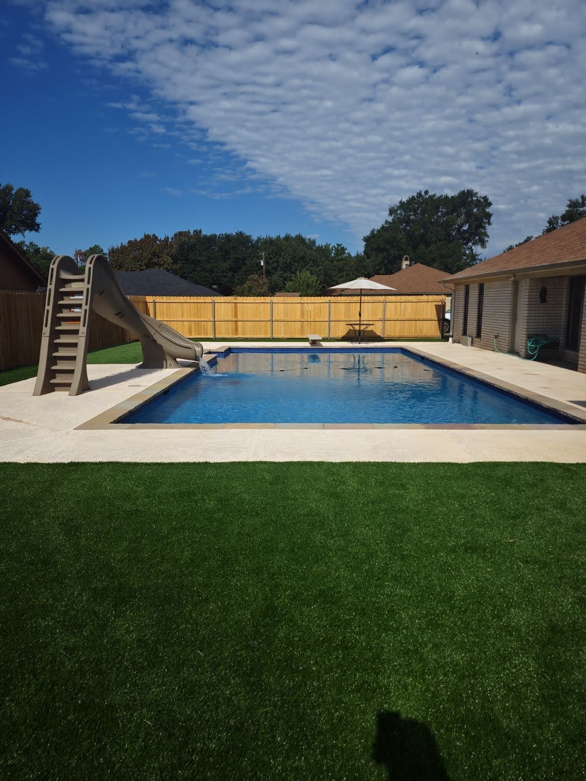 A large swimming pool with a slide in the backyard.