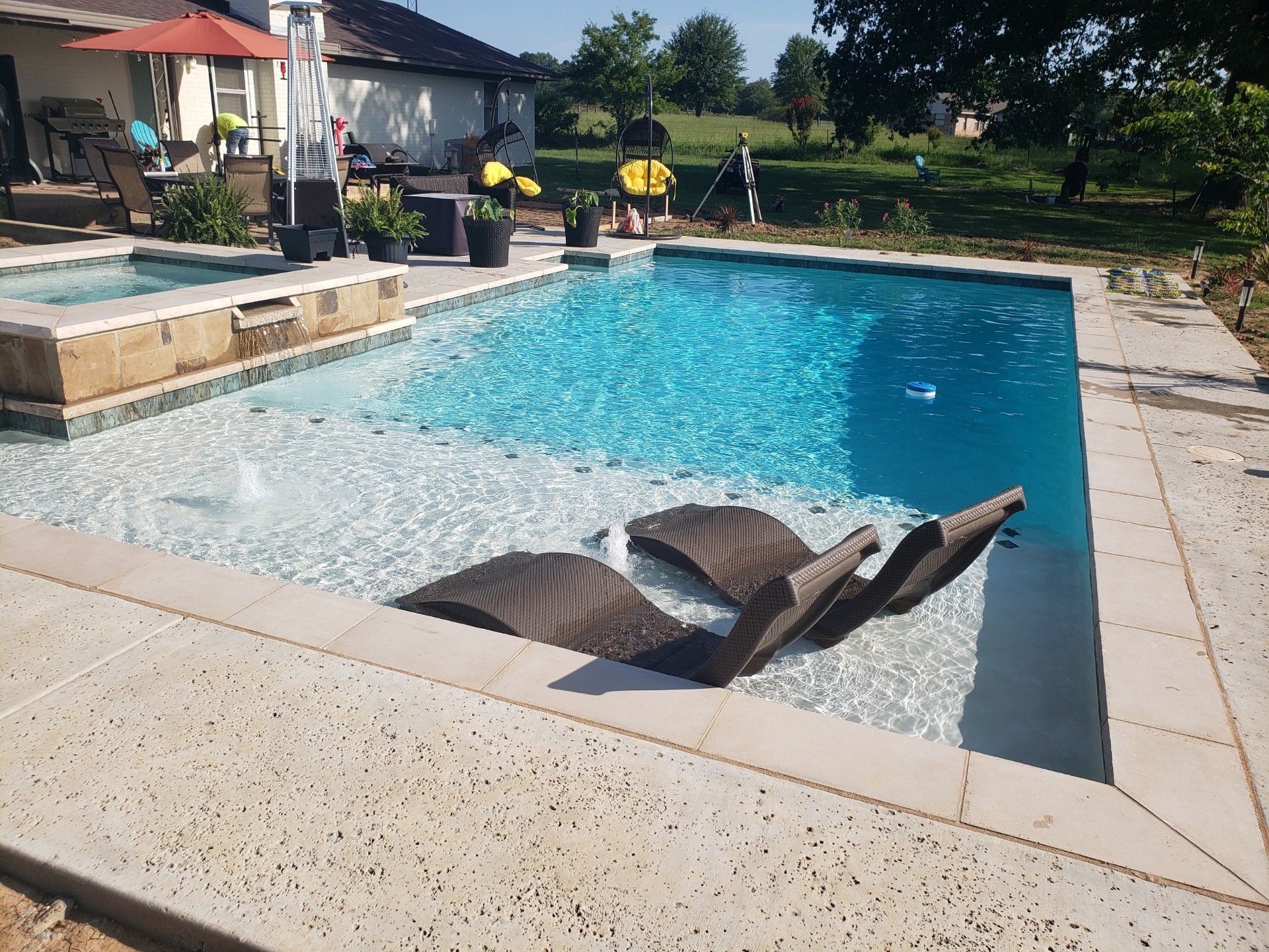 A large swimming pool with chairs in it and a house in the background.