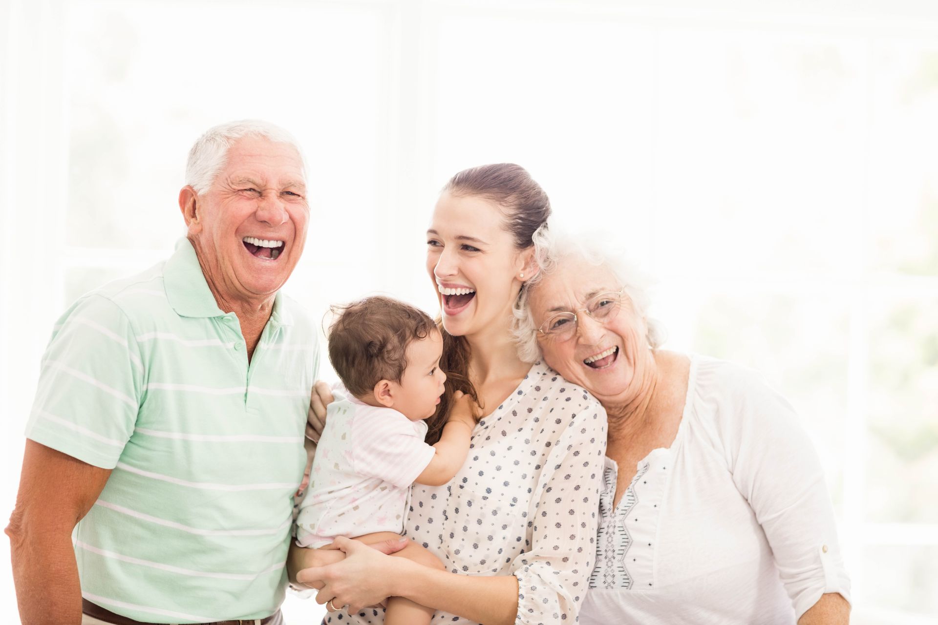 A woman is holding a baby while standing next to her grandparents.
