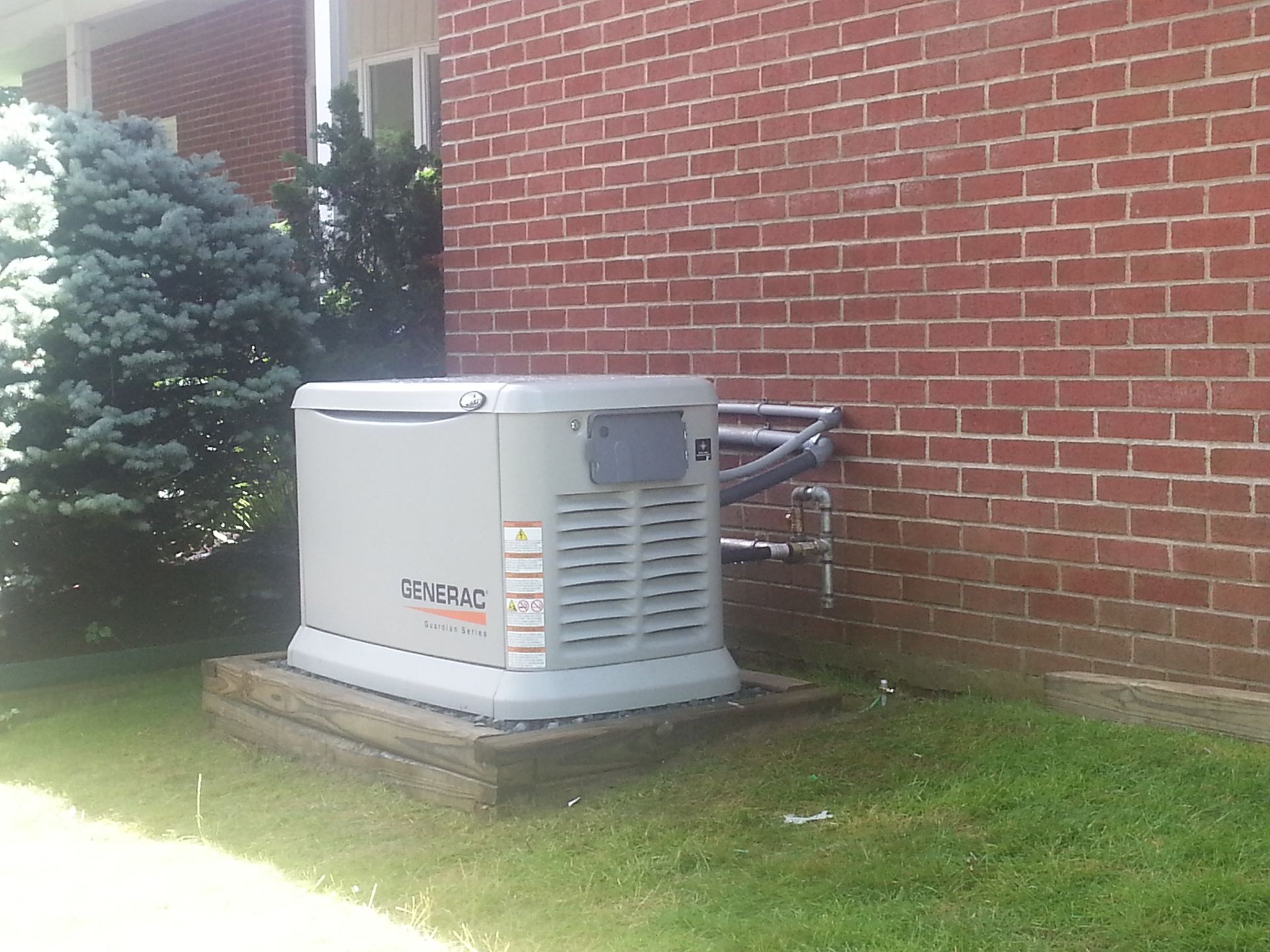 A generator is sitting on the side of a brick building