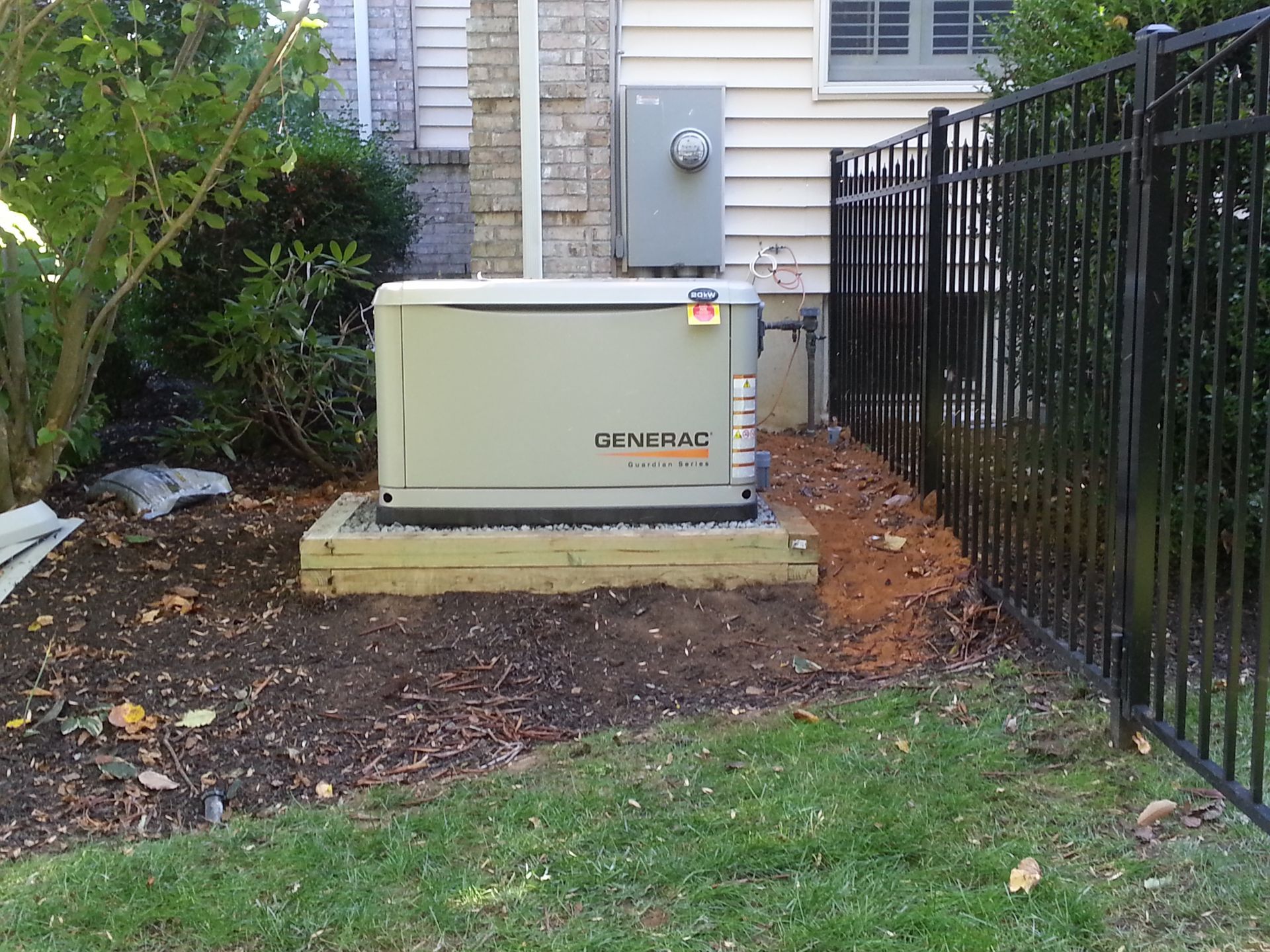 A generator is sitting in the backyard of a house