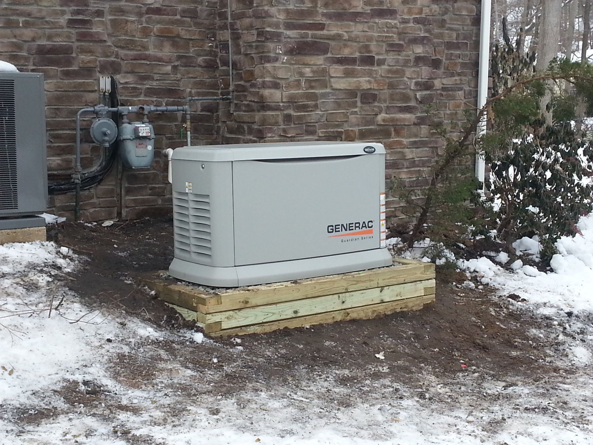 A generator is sitting on a wooden pallet in front of a brick building.