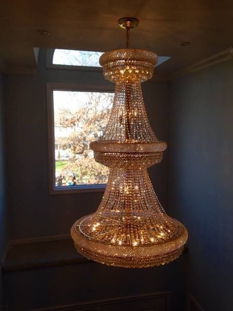 A large chandelier is hanging from the ceiling in a room next to a window.