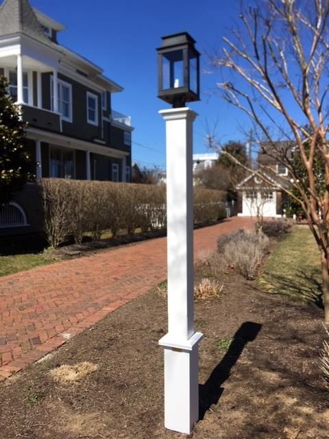 A white pole with a black lantern on top of it