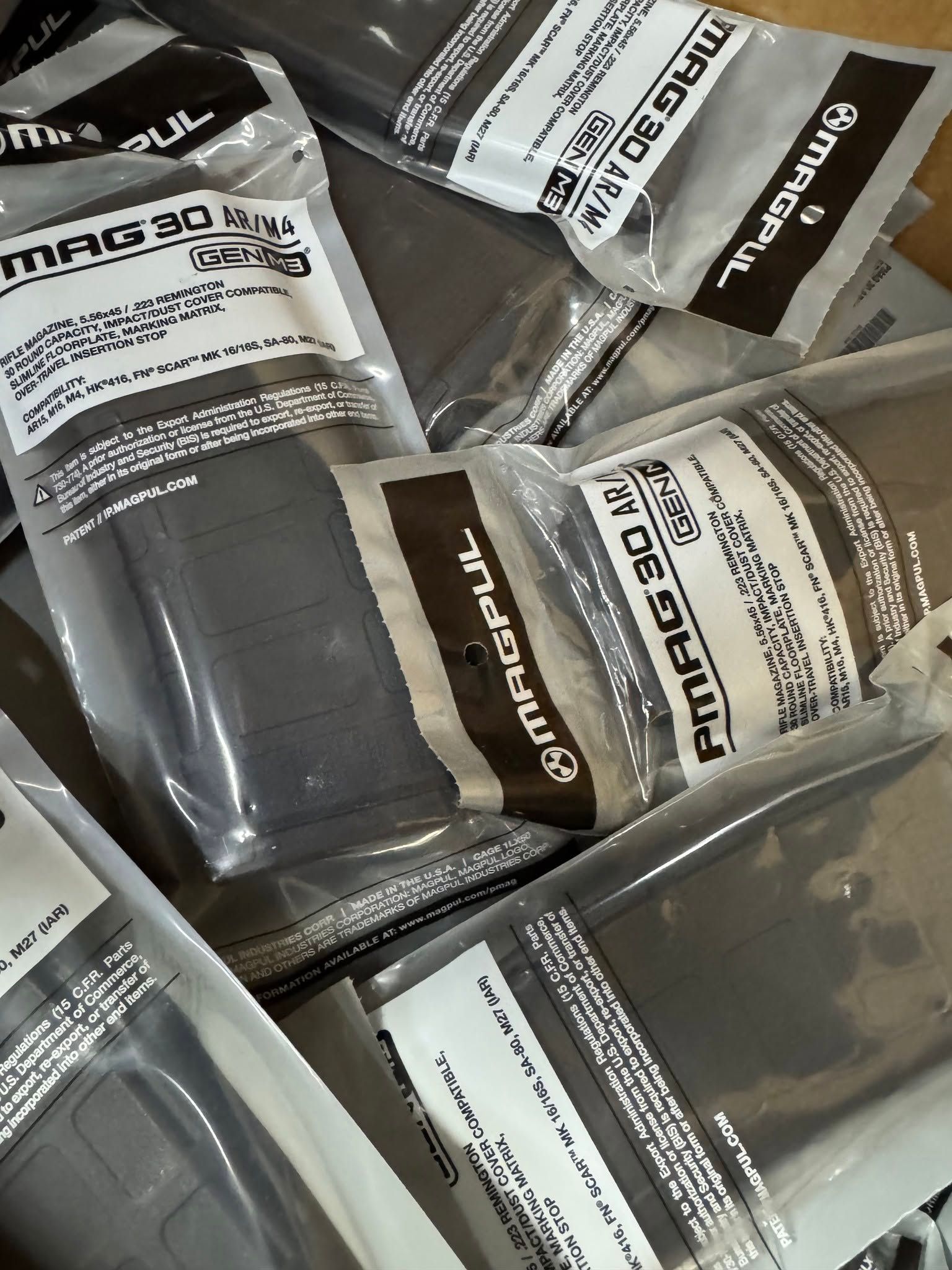 Assorted packaged products in a box, with black, white, and gray labels visible.