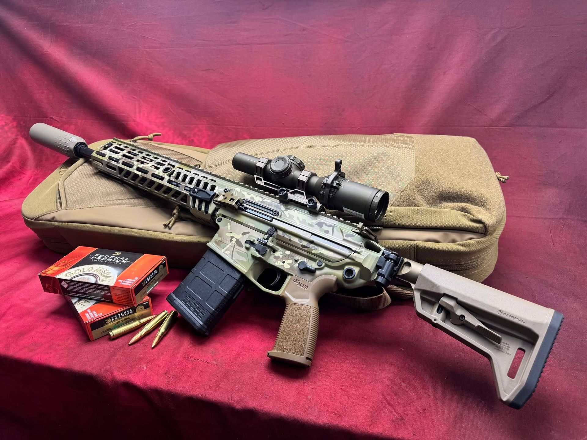 Rifle with scope and tan stock on a case, with ammunition boxes and cartridges on a red cloth background
