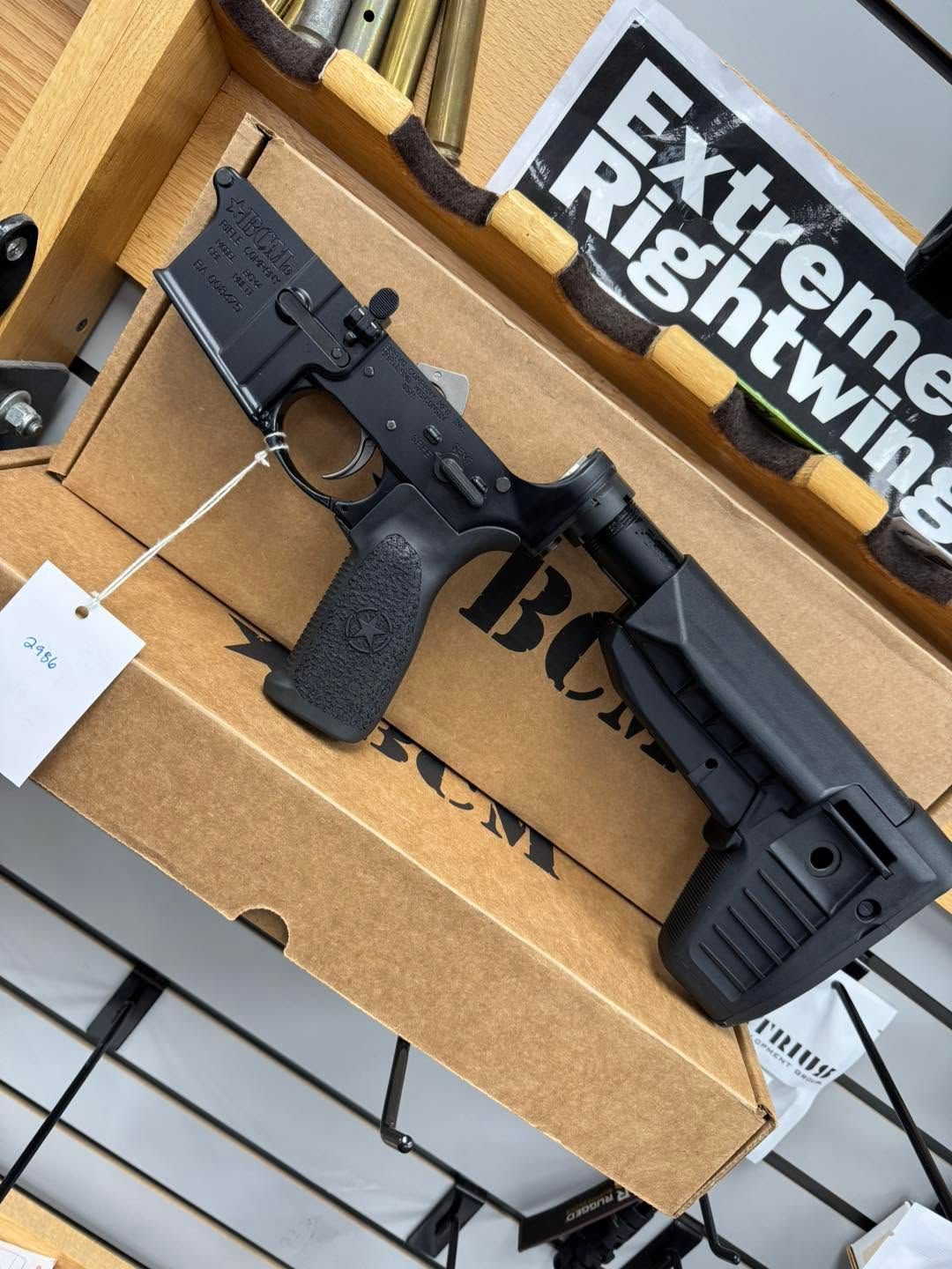 Black rifle with adjustable stock and pistol grip on a cardboard display box with a tag attached
