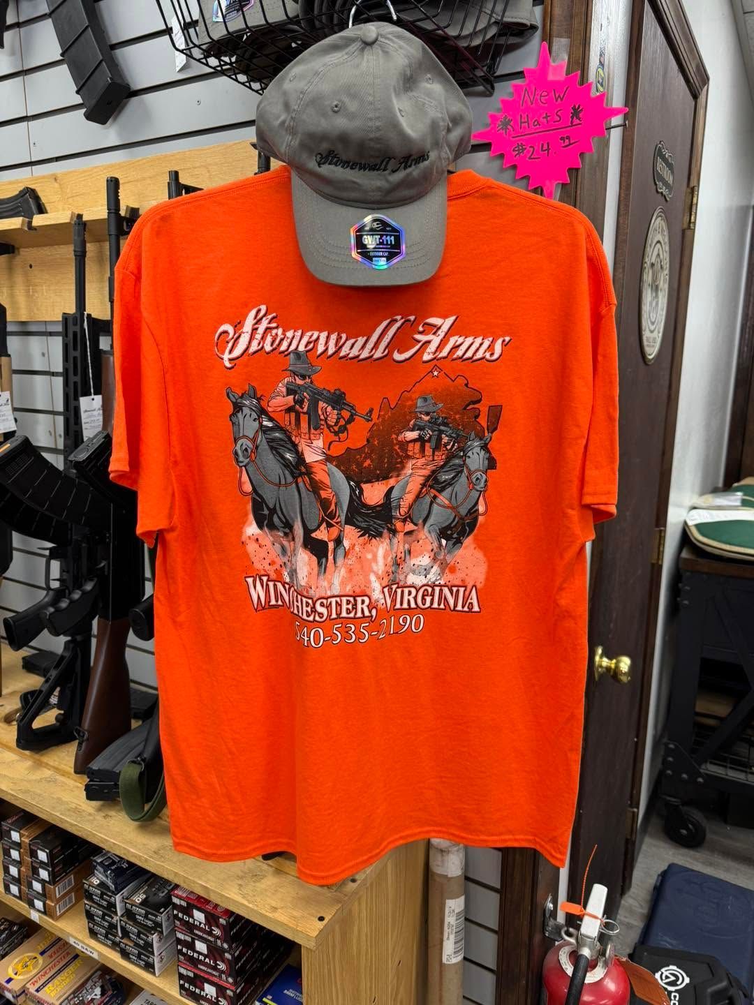 Orange graphic T-shirt with a shark and “Ninetails Arms” text hanging in a store display