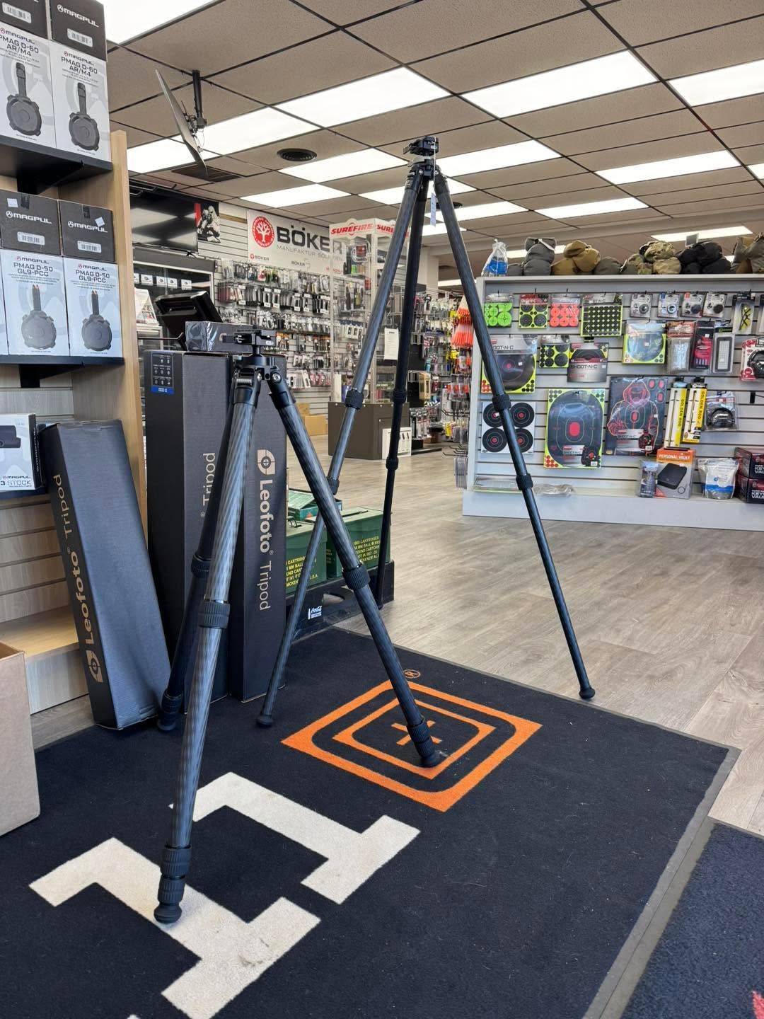 Store display of black tripod stands on a black mat in an indoor retail aisle