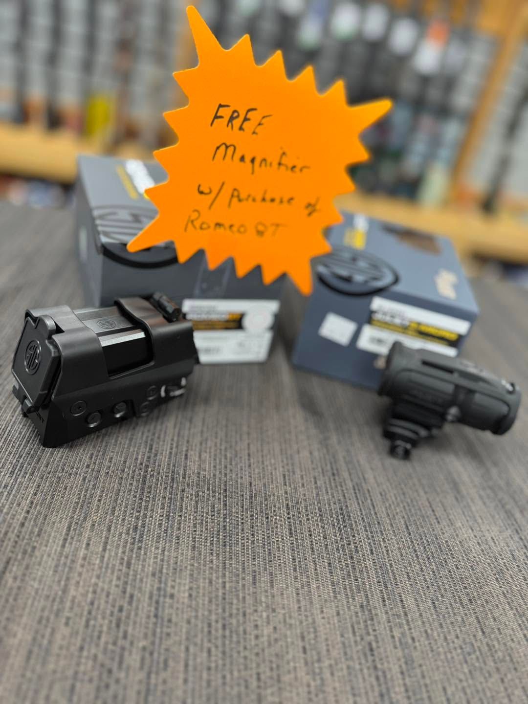 Miniature black trucks on a tabletop beside a bright orange starburst sale sign.