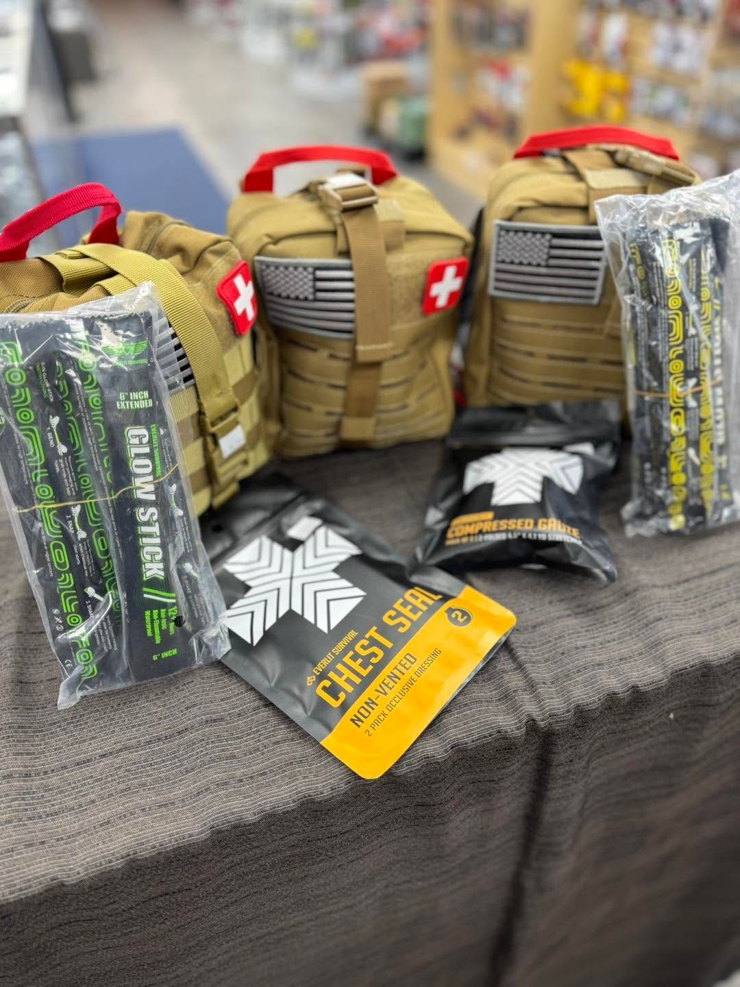 Tactical first aid kits and medical supplies laid out on a table, with red cross patches visible.