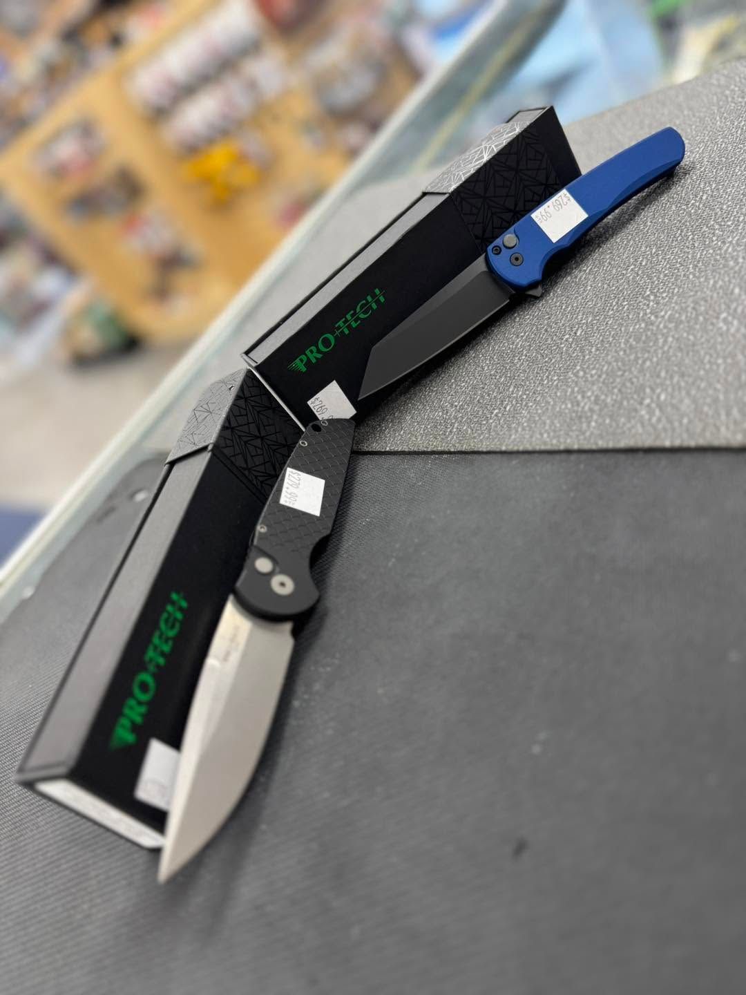 Two folding utility knives, one black and one blue, displayed on a store shelf.