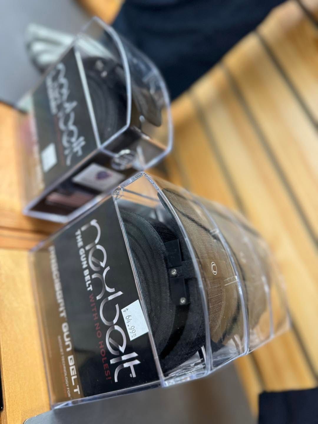 Two black packaged hair accessories on a wooden counter with clear plastic lids