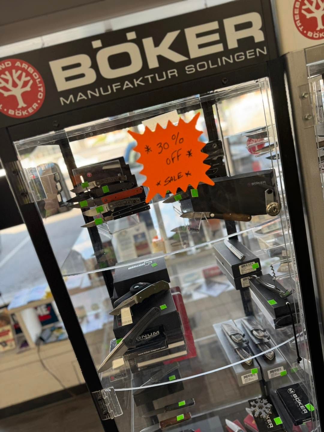 Glass display case at Böker Manufaktur Solingen, showing knives and an orange sale sign.
