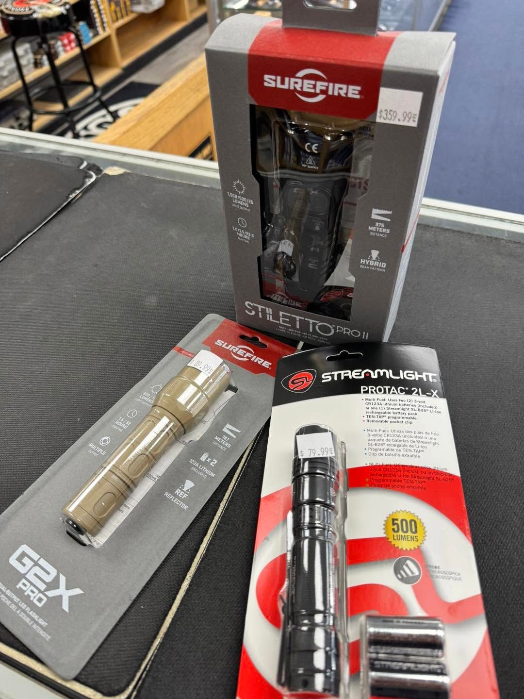 Assorted flashlights and accessories displayed on a black table with product packaging.
