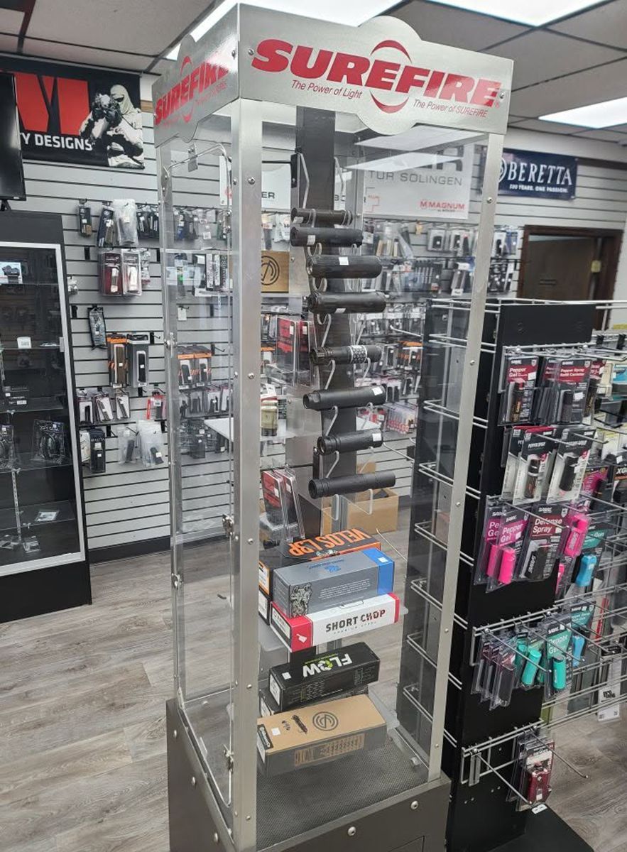 SUREFIRE display rack in an outdoor gear store, showing flashlights and accessories on clear shelves