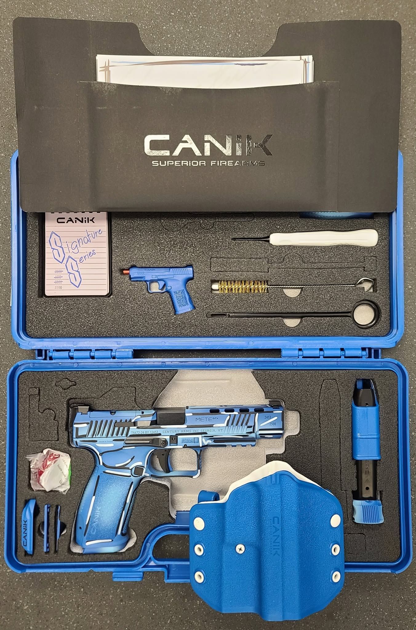 Blue pistol and accessories arranged in an open foam-lined case.