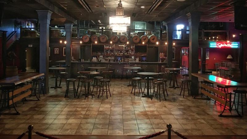 A large empty restaurant with tables and chairs and a bar.