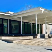 A modern house with a covered porch and stairs on a sunny day.
