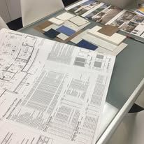 A table with a lot of papers on it and a drawing of a house on it.