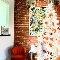 A white christmas tree is in a living room with a brick wall.