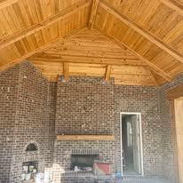 There is a fireplace in the middle of the room with a wooden ceiling.