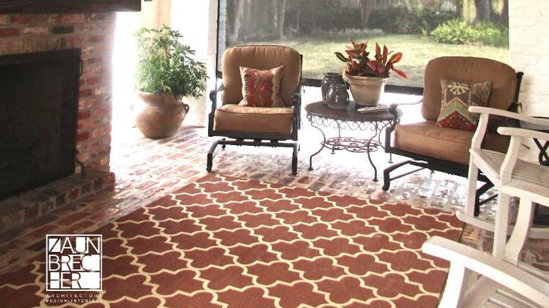 A living room with a rug and chairs and a fireplace