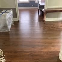 Empty room with wood-look floor, white walls, and a bed and table at the edges