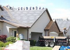 Suburban house with damaged roof shingles and a work truck in the driveway