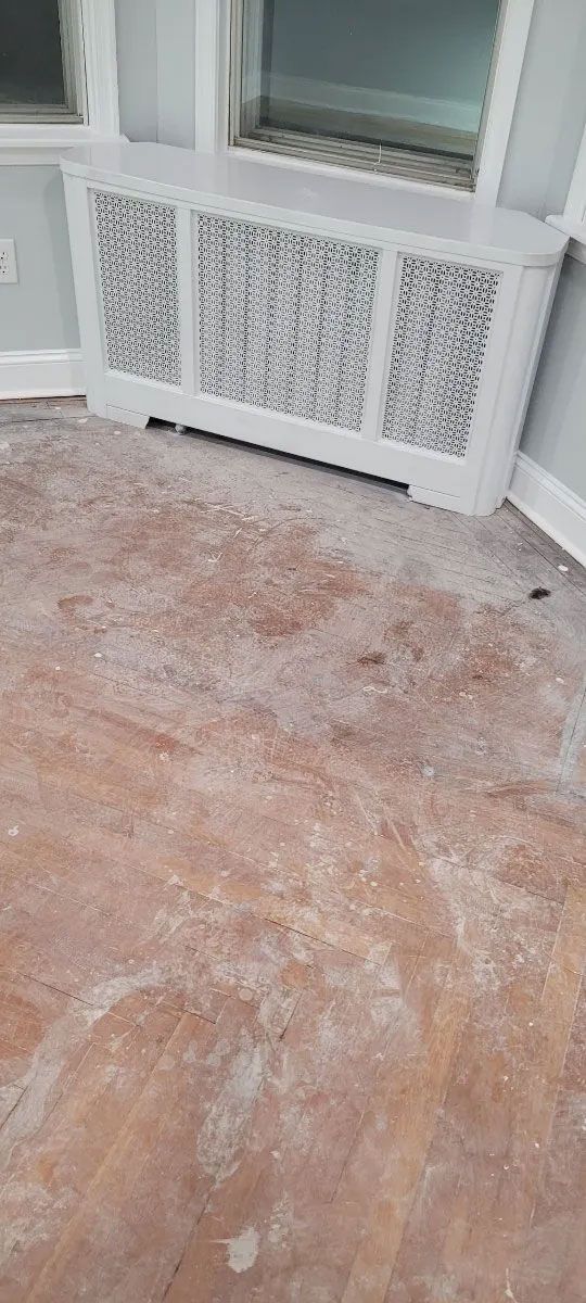 A room with a white radiator cover on the floor.