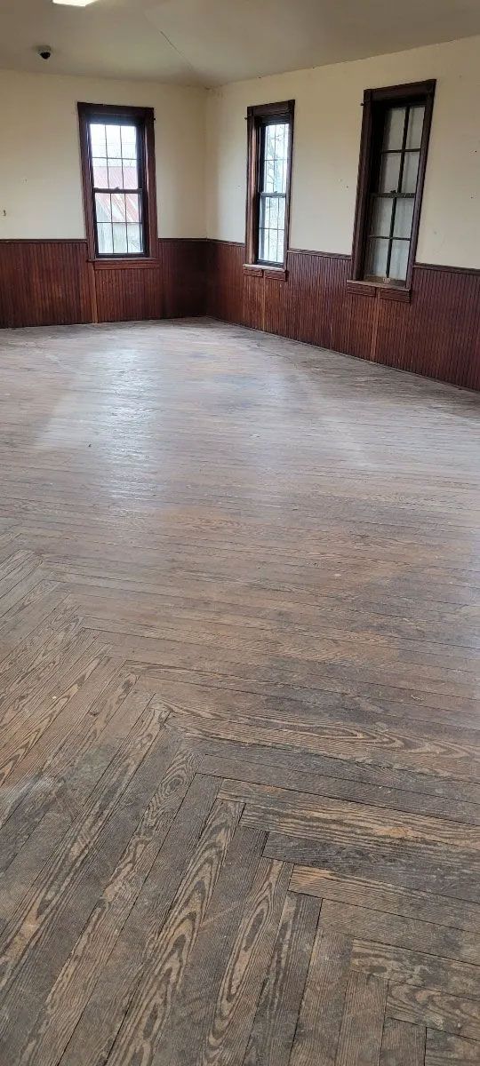 An empty room with a wooden floor and windows.