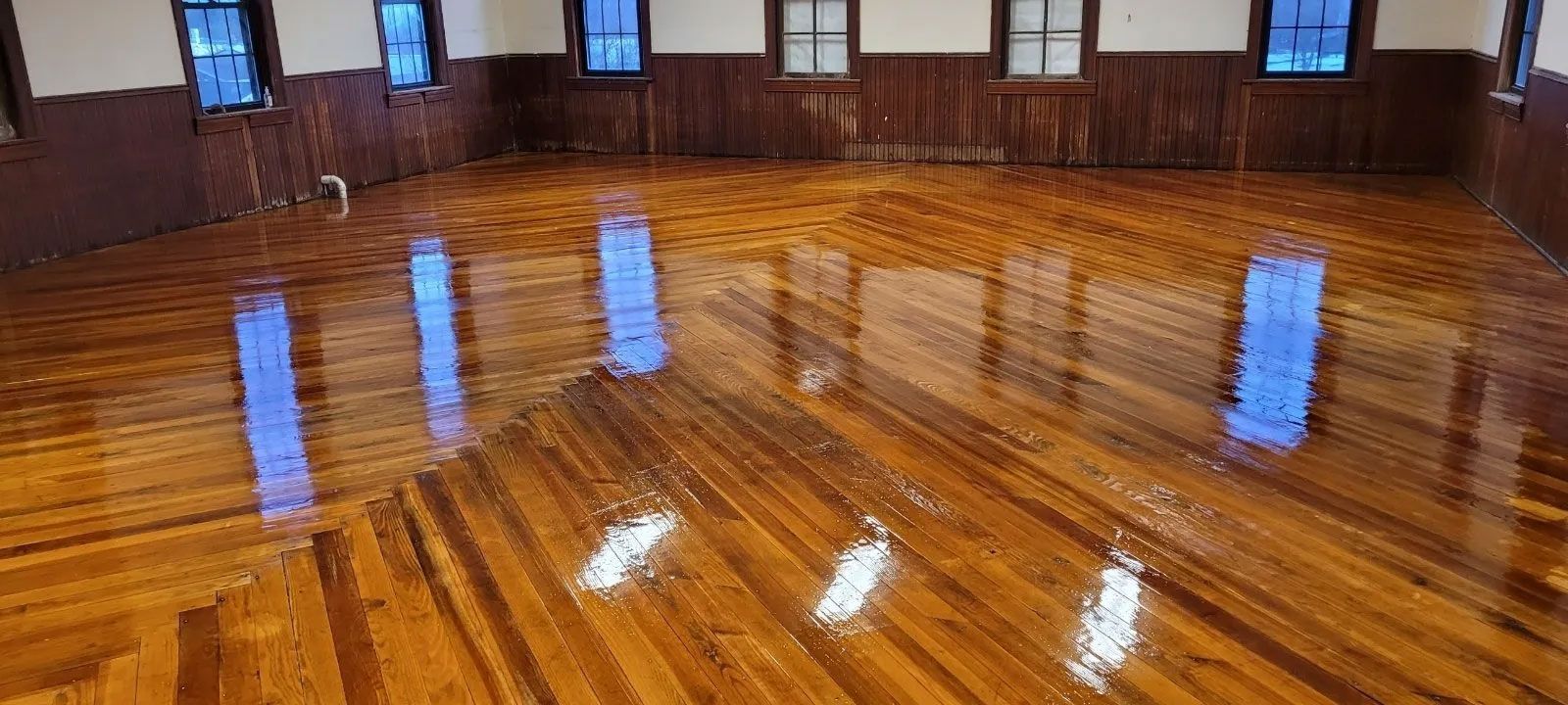 A large room with a wooden floor and windows.