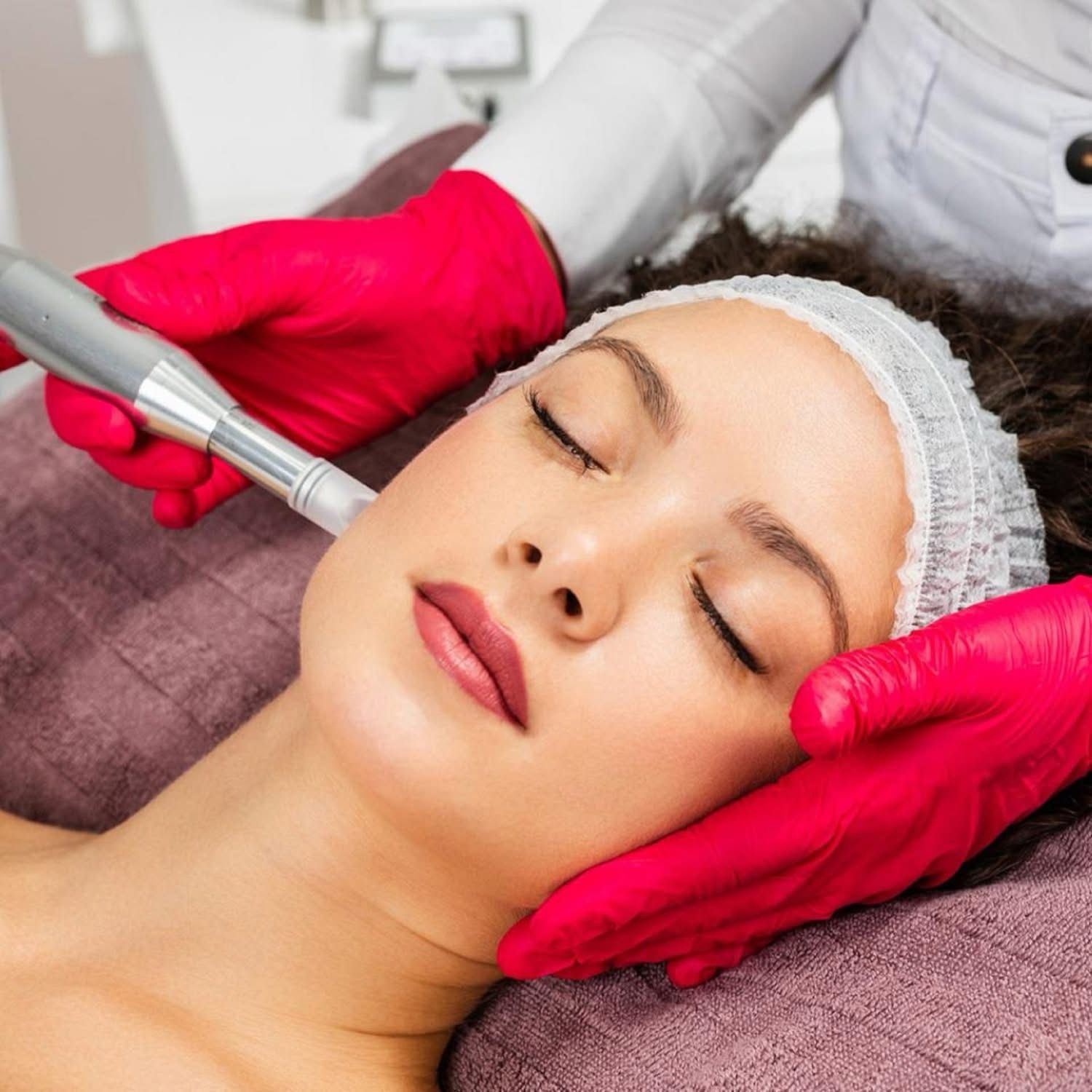 A woman is getting a facial treatment with her eyes closed