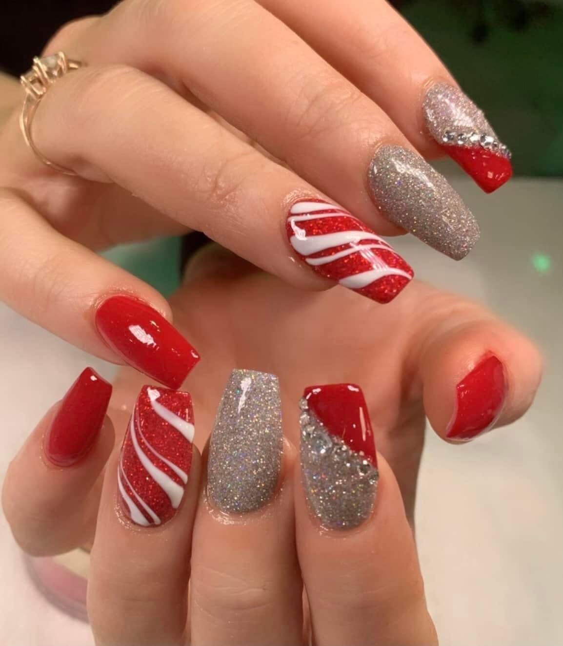 A woman 's nails are painted red and gray with a candy cane design