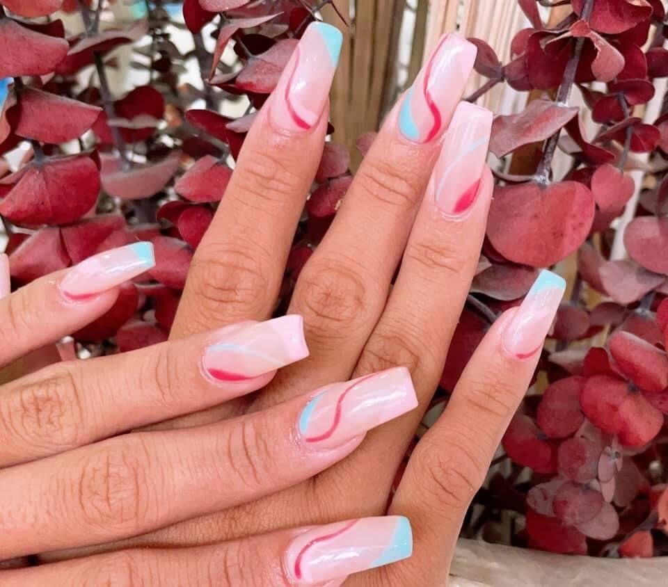 A close up of a person 's nails with a plant in the background.